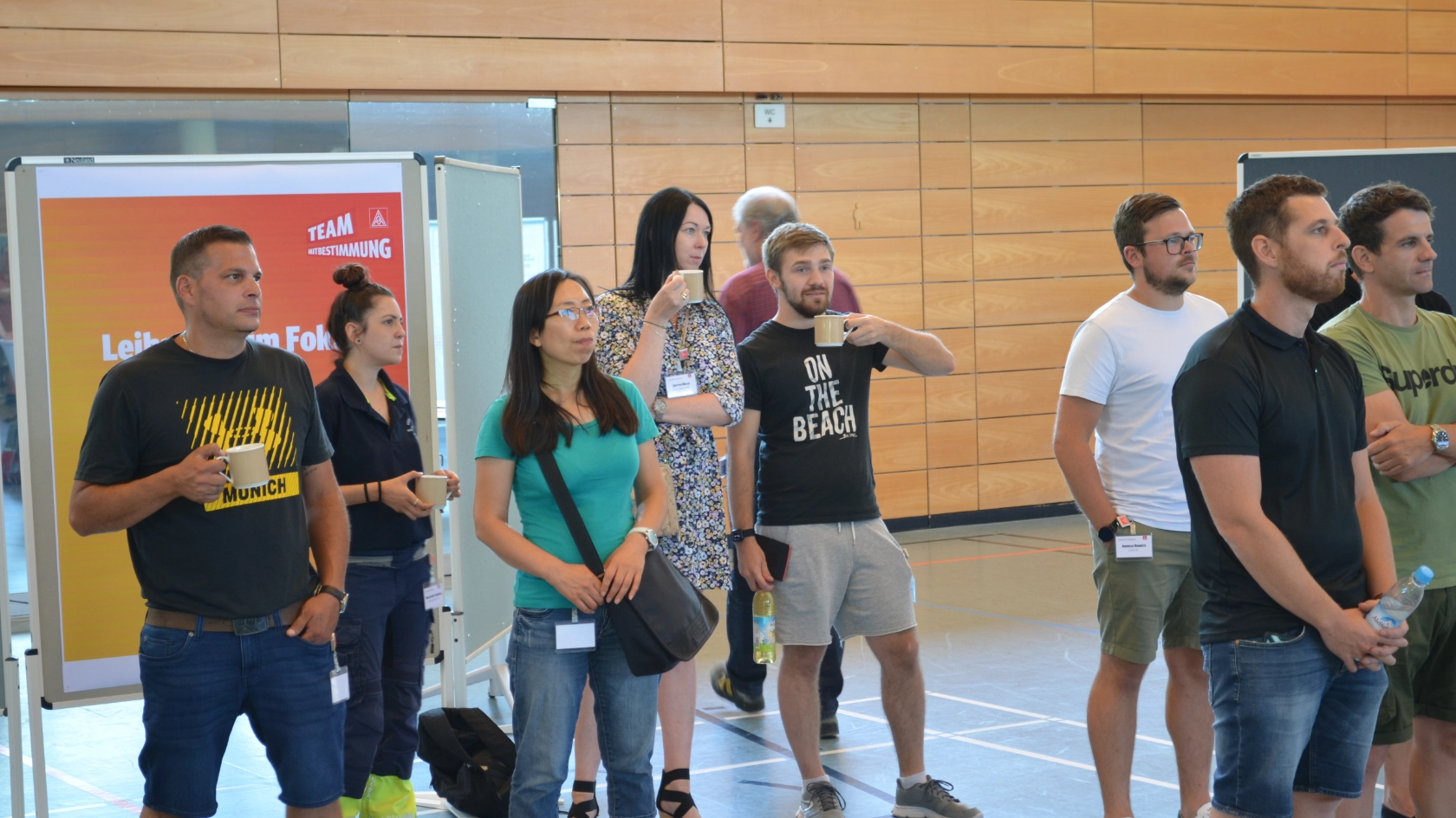 Kolleg*innen stehen vor dem Infopoint zum Thema Leiharbeit und schauen zur Bühne in die Mitte