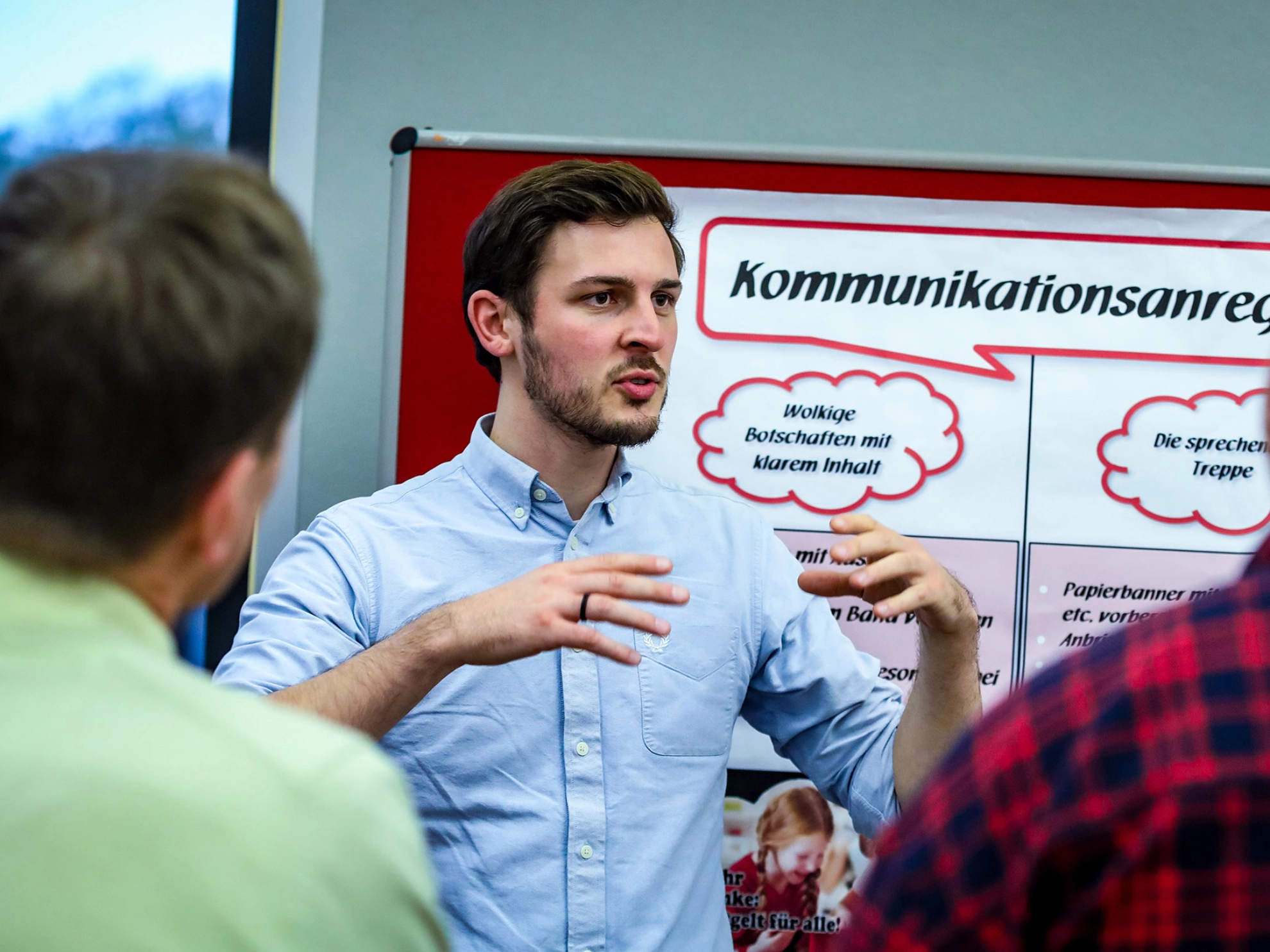Junger Mann steht vor Flipchart und erklärt etwas.