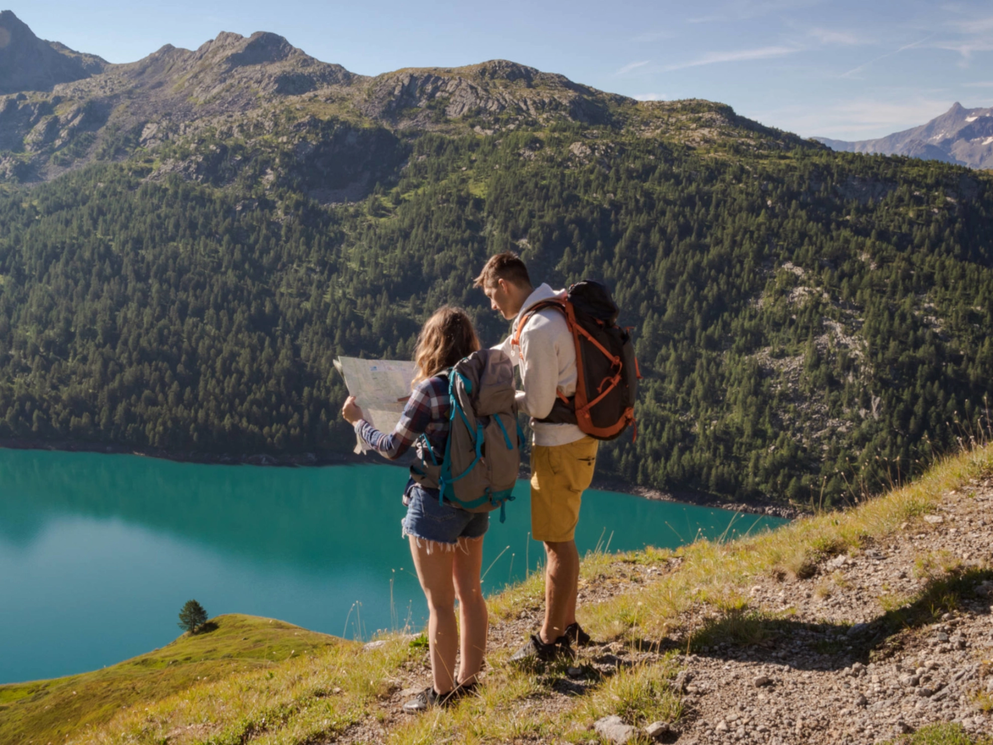 Ein junges Paar steht auf einem Wanderweg und liest eine Karte.