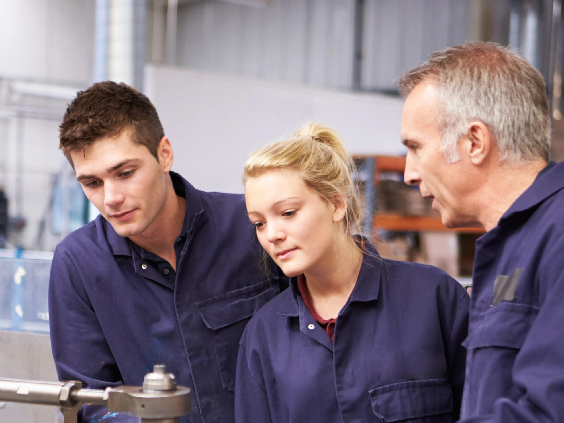 Ingenieur erklärt zwei Auszubildenden eine Maschine