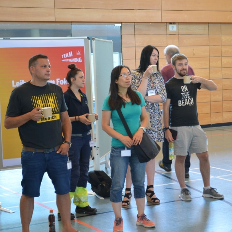 Kolleg*innen stehen vor dem Infopoint zum Thema Leiharbeit und schauen zur Bühne in die Mitte