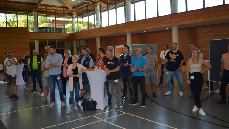 Teilnehmer schauen auf die in der Mitte liegende Bühne